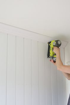 a man is using a drill to paint the walls in his house with white boards