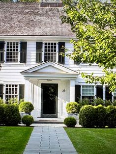 a white house with black shutters and green grass