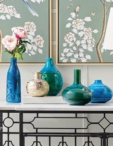 three vases are sitting on a table with flowers and birds painted on the wall behind them