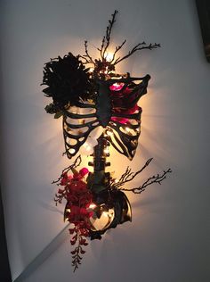 a light that is on the wall next to some branches and flowers with lights in them