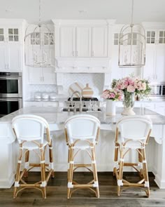 three white chairs sitting in front of a kitchen island