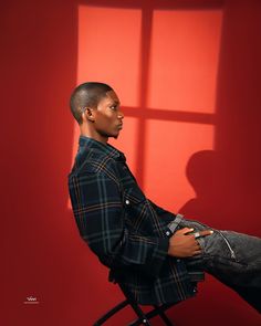 a man sitting in a chair with his feet up against the wall and looking off into the distance