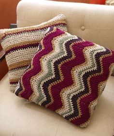 two crocheted pillows sitting on top of a white couch