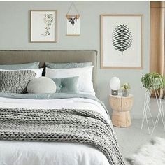 a bed with white sheets and pillows in a bedroom next to two pictures on the wall