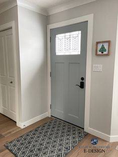 an empty room with a gray door and black rug on the floor in front of it