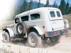 an old white truck driving down a dirt road