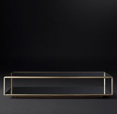 a glass and brass coffee table on a black background