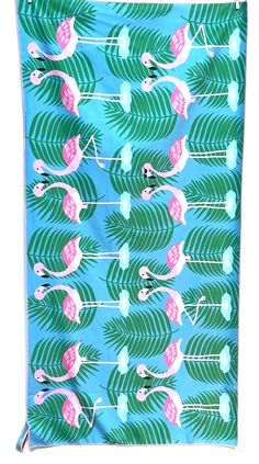 a blue and pink towel with flamingos on it's sides, surrounded by palm leaves