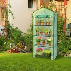 a green house with potted plants in the front yard and on top of it