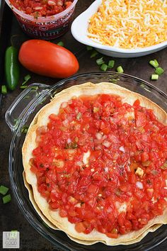 an uncooked pizza sitting on top of a pan next to other food items