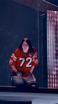 a woman sitting on top of a bench wearing a football uniform