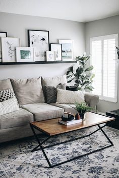 a living room with a couch, coffee table and pictures on the wall above it