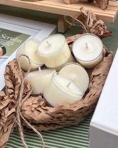 some white candles are in a basket on a table