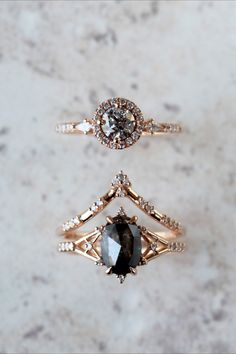 three different types of engagement rings on a marble surface with white and black diamonds in the middle