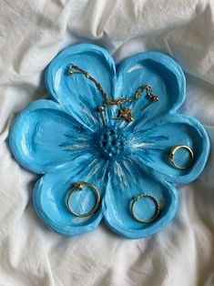 a blue flower shaped tray with gold rings on it