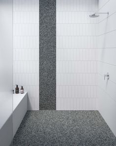 a white tiled bathroom with black and white tile on the walls, shower head, and bathtub