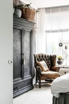 a bedroom with a bed, chair and armoire