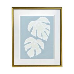 two white leaves in a gold frame on a blue background, one is framed and the other is mounted