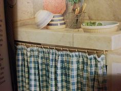 a kitchen with a sink, window curtain and potted plants