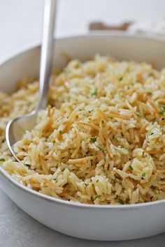 a white bowl filled with rice and garnished with parsley