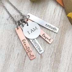 three different necklaces that say i am enough to be proud on the front and back