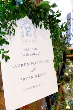 a welcome sign with greenery on it is hanging from a pole in the center of a room