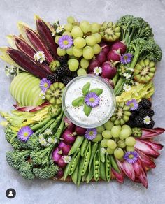 an arrangement of fruits and vegetables arranged in a circle with a small bowl on top