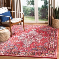 a red rug with an ornate design on it in front of a chair and window