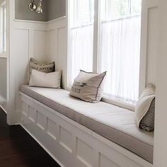 a white window seat with pillows on it