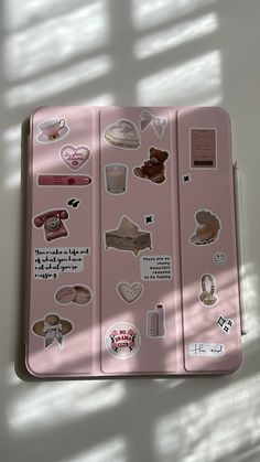 a pink case with various stickers on it sitting next to a white table top