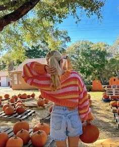 a woman is standing in front of pumpkins