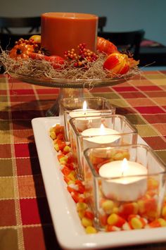 there are many candles on the table and in the centerpieces with autumn decorations