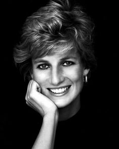 a black and white photo of a woman with her hand on her chin, smiling