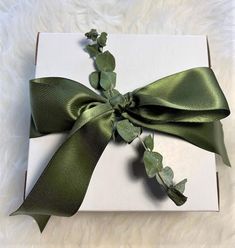 a white box with green ribbon and ivy on it