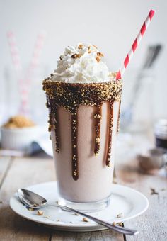 a chocolate milkshake topped with whipped cream and sprinkles on a white plate