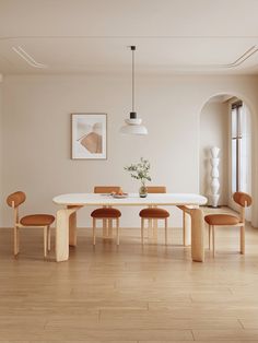 a dining room table with four chairs and a vase on the table in front of it