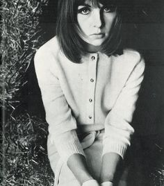 black and white photograph of a woman sitting on the ground with her hands in her pockets