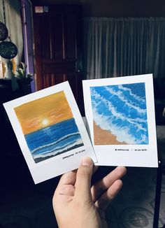 someone holding up two cards with watercolors on them