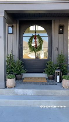 the front door is decorated with wreaths and potted plants