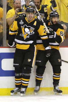 the penguins are celebrating on the ice with their arms around each other as they stand in front of an audience