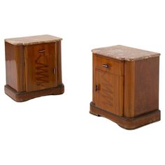 two wooden nightstands with marble tops on each side, one has a drawer and the other has a door