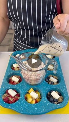 a person in an apron mixing ingredients into a cupcake tin on a blue tray