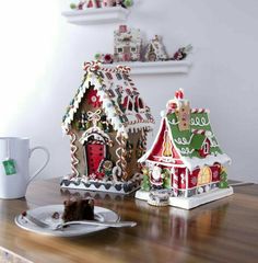 two gingerbread houses on a table with a cup of coffee in front of them