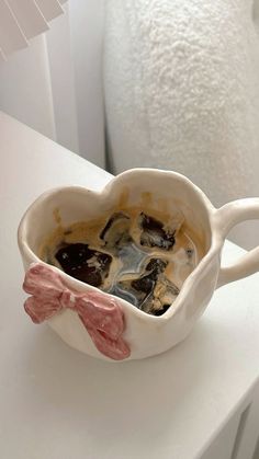 a heart shaped bowl with ice in it sitting on a table next to a white vase