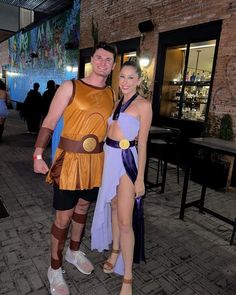 a man and woman in costume standing next to each other on a brick floored walkway