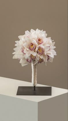 a bouquet of flowers sitting on top of a white table next to a gray wall