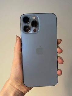 a person holding an iphone in their left hand with the back cover partially open to show it's camera lens