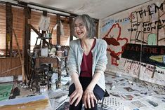 a woman sitting on top of a chair in a room filled with books and papers