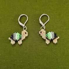 the earrings are made out of legos and have green, white, and black beads