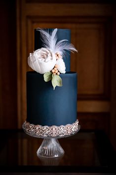 a black and blue wedding cake with feathers on top